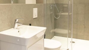 A modern bathroom with a glass-enclosed shower, a white sink, and a toilet. - rent24 Apartments & Suiten P180 (Berlin)