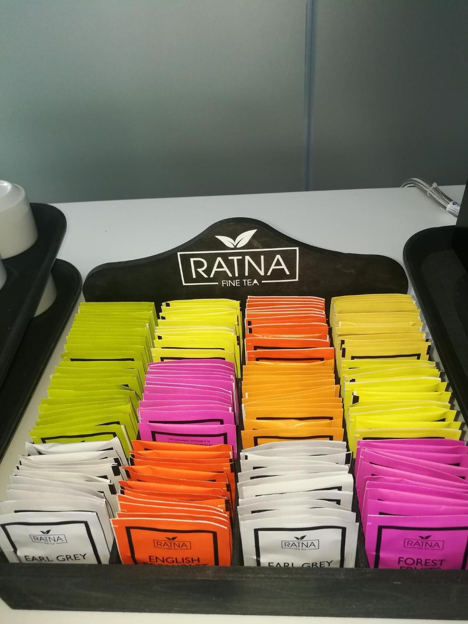 A tray with neatly organized tea bags labeled with different flavors like Earl Grey, English, and Forest.