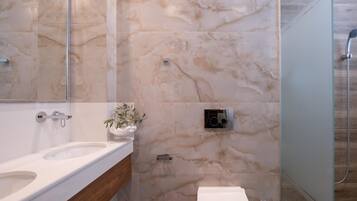 Ein modernes Badezimmer mit Marmorwand, einer Duschkabine aus Glas und einem Holzbadezimmer-Möbel.