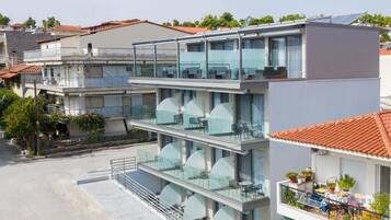 A modern multi-story hotel with glass balconies, outdoor seating, and a rooftop terrace.