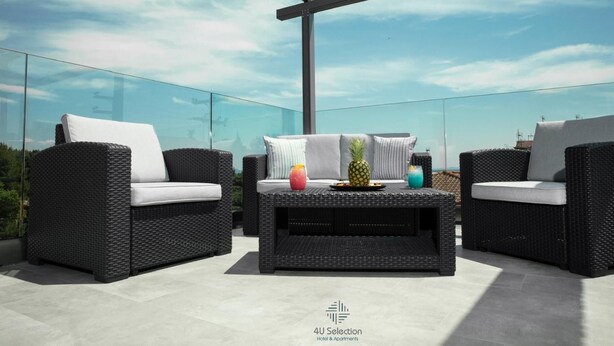 A rooftop terrace with wicker furniture and a glass balustrade. - 4-You (Polygyros)