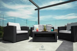 A rooftop terrace with wicker furniture and a glass balustrade. - 4-You (Polygyros)