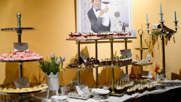 A buffet table with various desserts and a framed portrait on the wall. - Deutsches Haus (Waal)