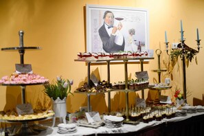 A buffet table with various desserts and a framed portrait on the wall. - Deutsches Haus (Waal)