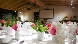 A dining table set with white tableware and vases of flowers. - Deutsches Haus (Waal)