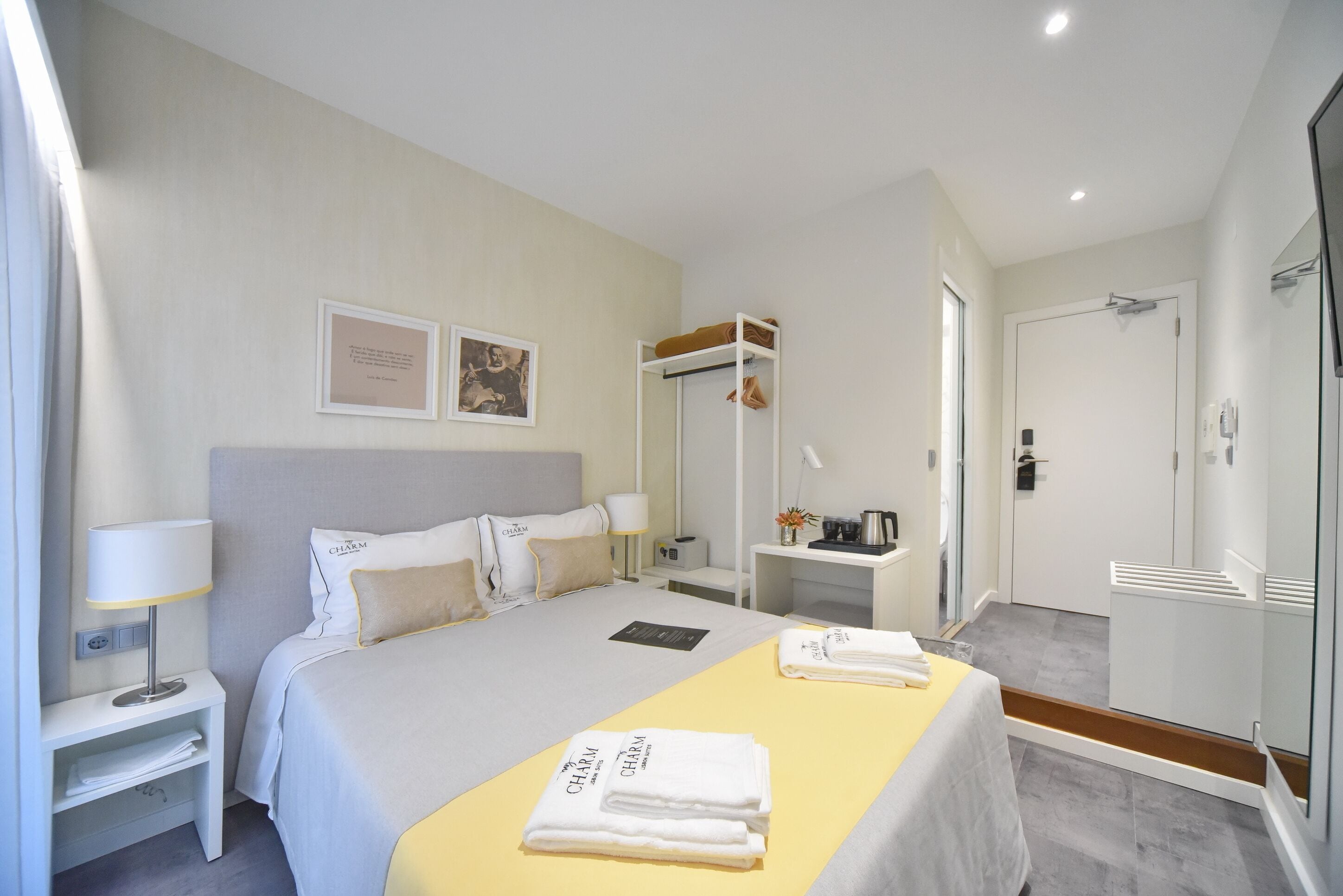 Una habitación de hotel con una cama, mesita de noche, lámpara y un pequeño escritorio con una silla.