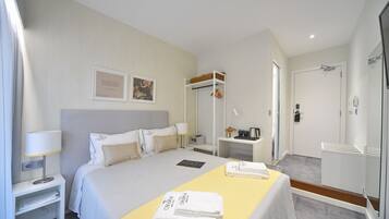 Una habitación de hotel con una cama, mesita de noche, lámpara y un pequeño escritorio con una silla.
