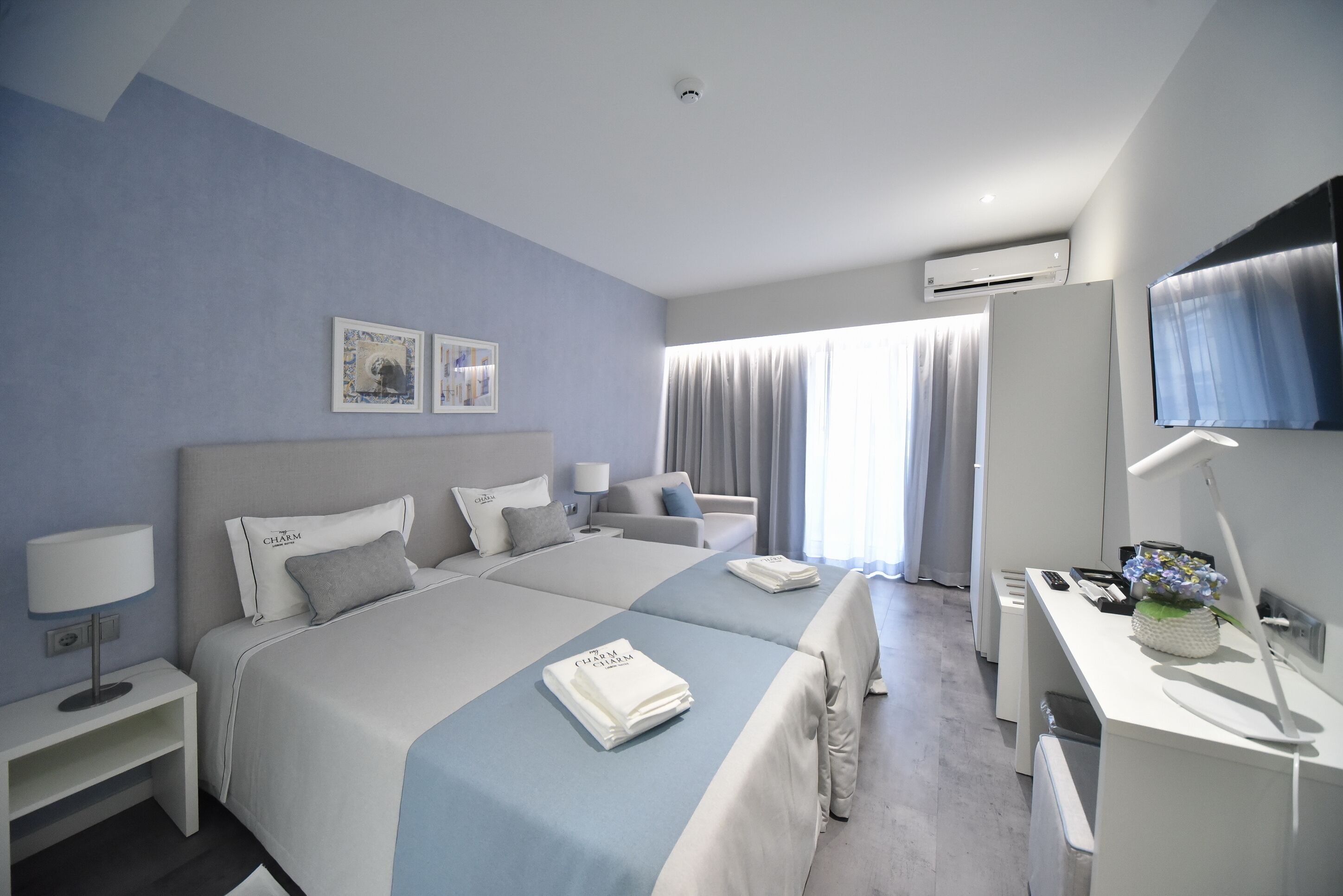 A modern hotel room with a large bed, a desk, and a TV.