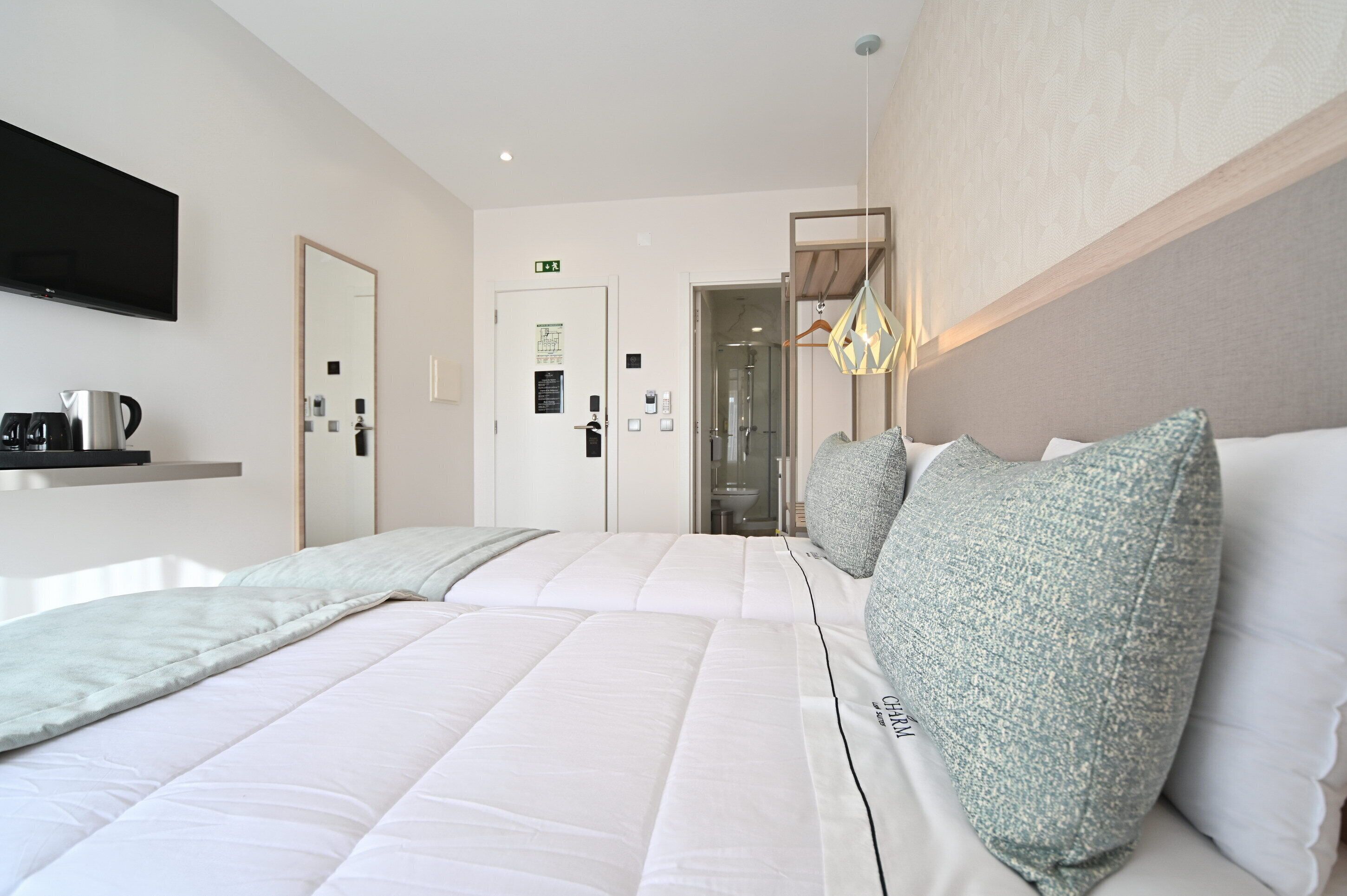 A hotel room with a large bed, a flat-screen TV mounted on the wall, a coffee machine, and a mirror.