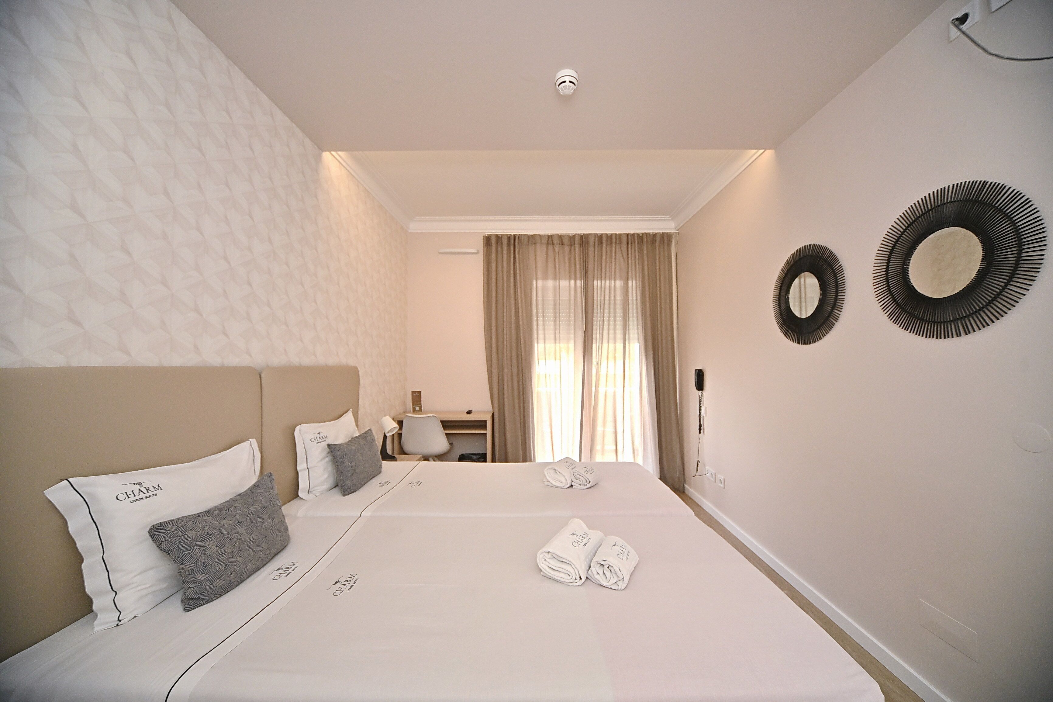 Quarto de hotel com uma cama grande, duas almofadas, uma mesa e uma cadeira.
