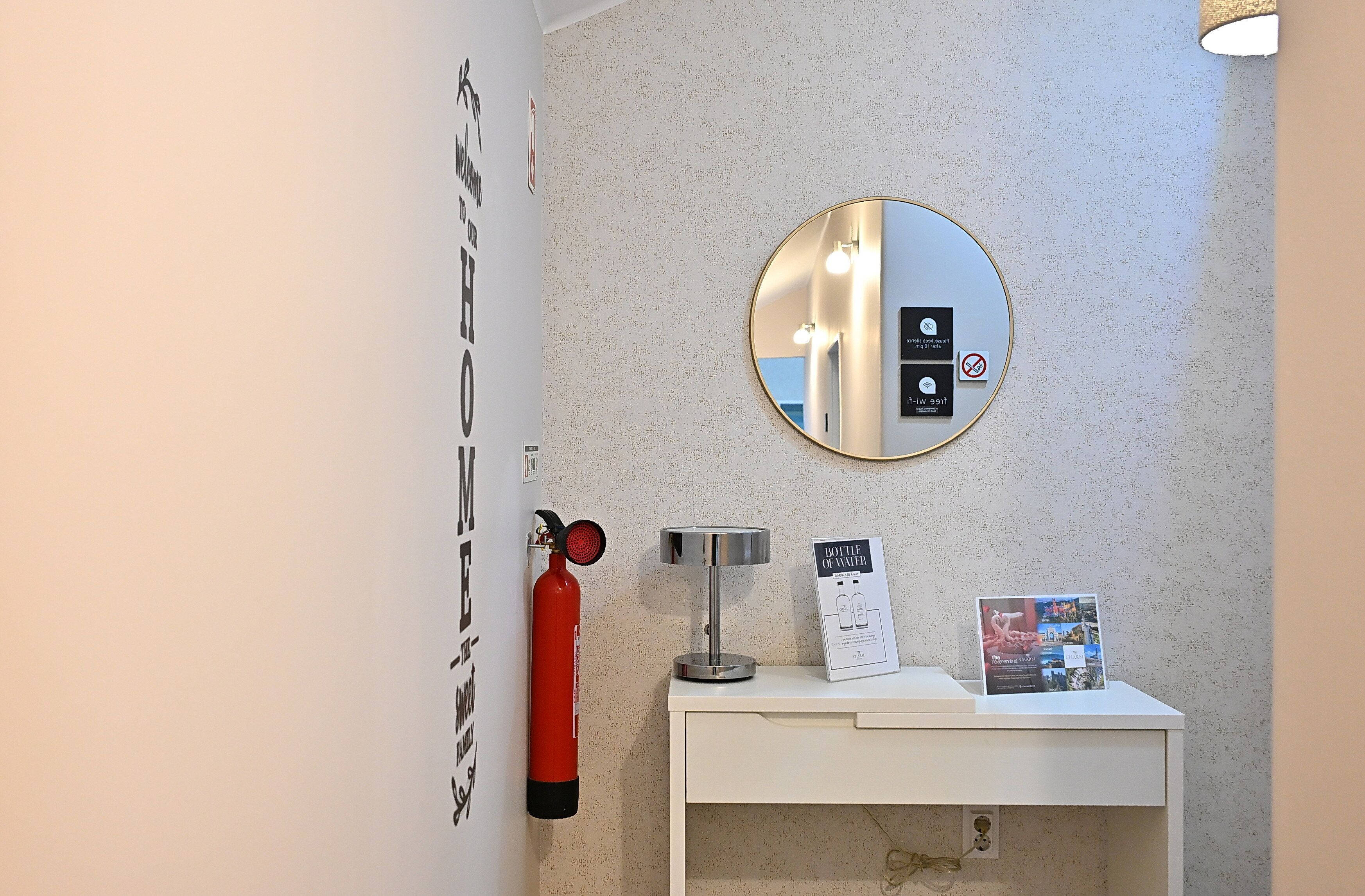 A bathroom with a round mirror, a fire extinguisher, a water dispenser, and a sign indicating the bottle of water is available.