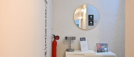A bathroom with a round mirror, a fire extinguisher, a water dispenser, and a sign indicating the bottle of water is available.
