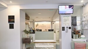 A hotel reception area with a reception desk, a digital screen, and a seating area.