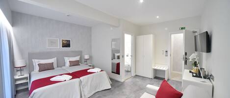 Una habitación de hotel moderna con una cama grande, mesitas de noche, un área de descanso y un baño con espejo y lavamanos.