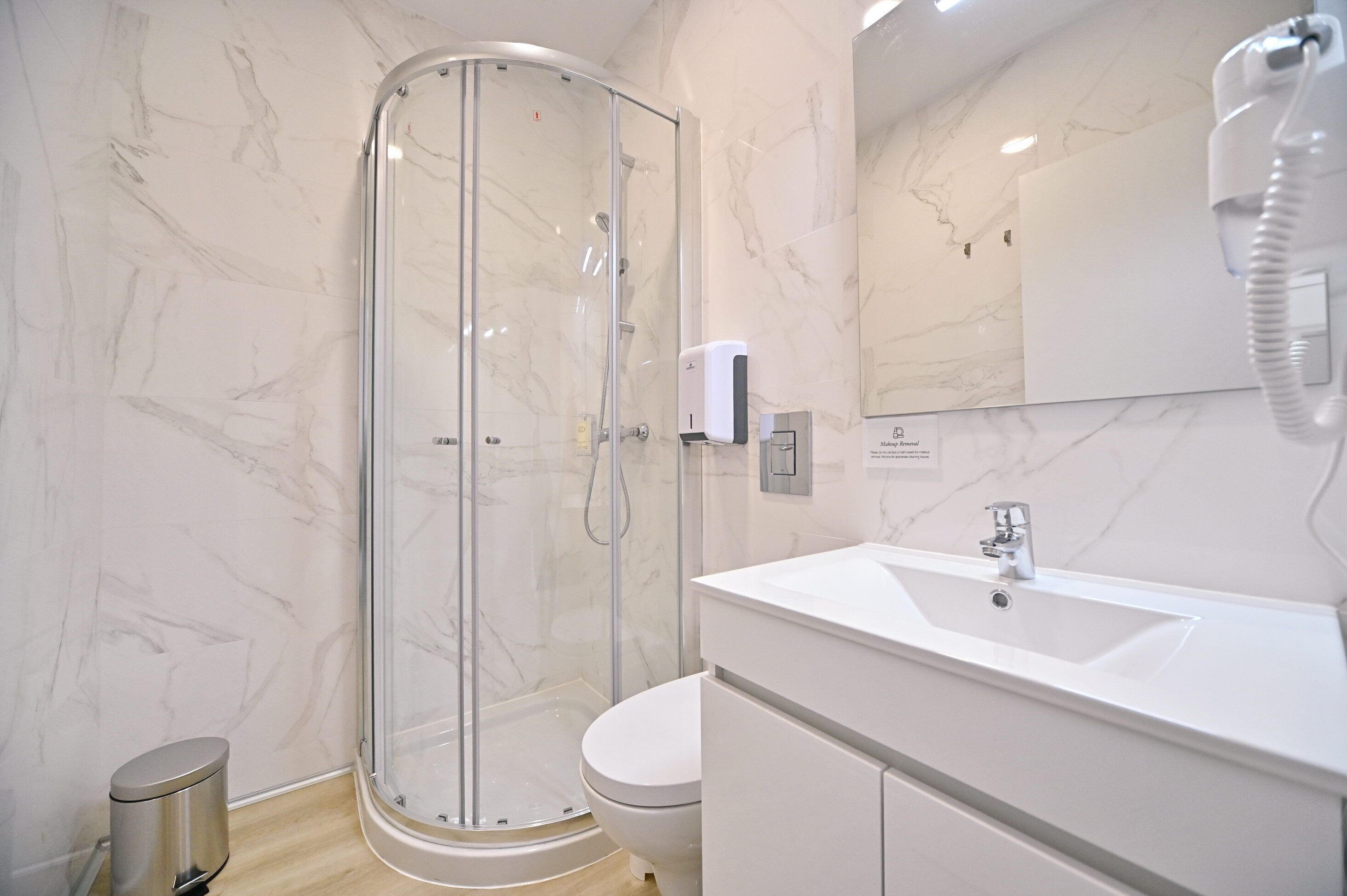 A modern bathroom with a glass-enclosed shower, a white sink, and a toilet.