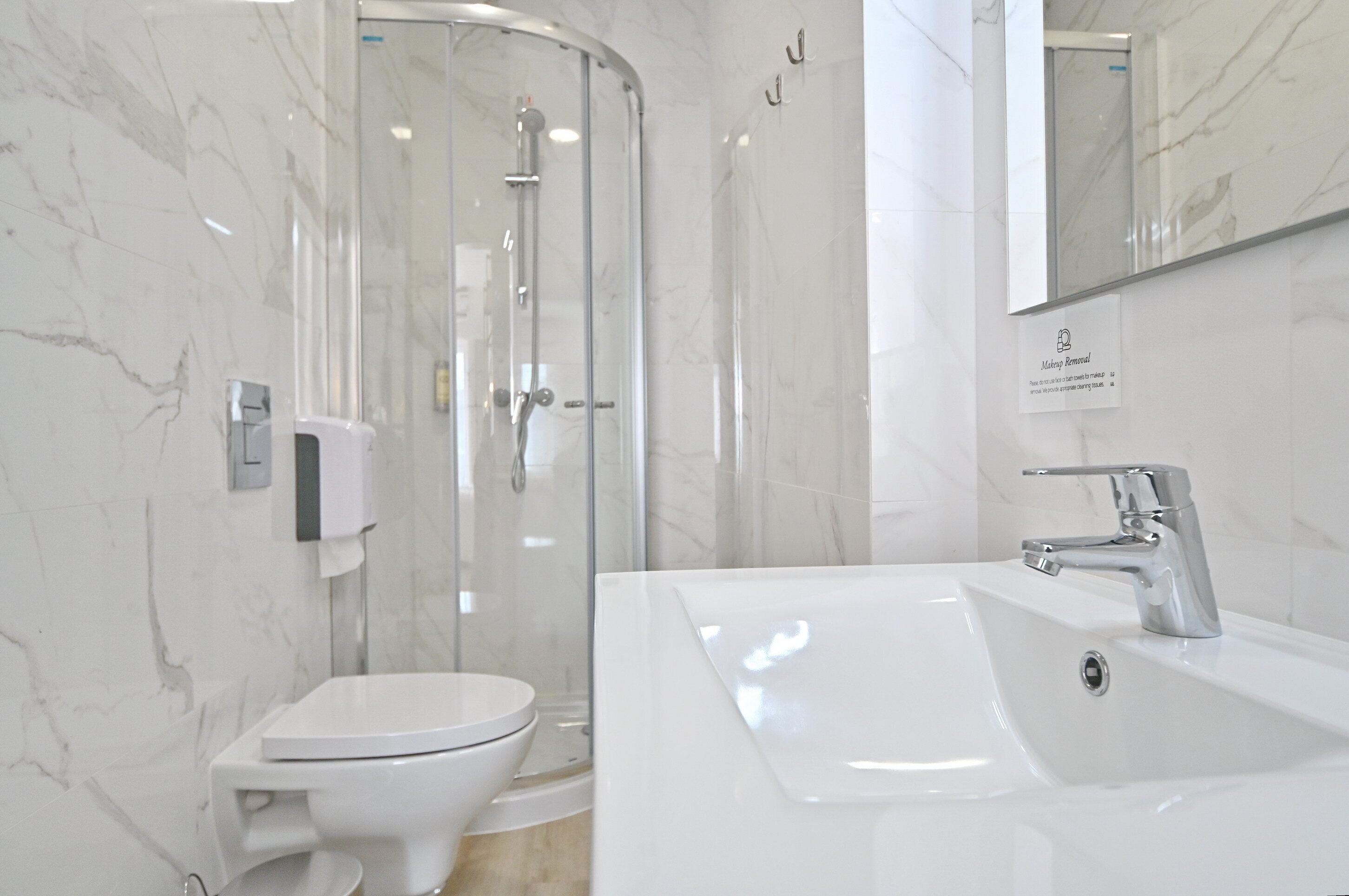 A modern bathroom with a glass-enclosed shower, a white sink, and a toilet.