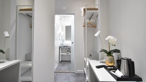 A modern bathroom with a white sink, mirror, and towel rack. There is a white orchid in a vase on the counter.