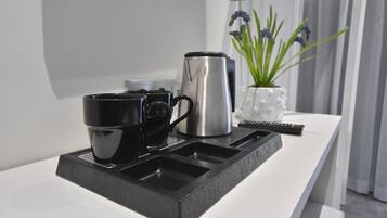 Eine moderne Küchenarbeitsplatte mit einer Kaffeemaschine, zwei schwarzen Tassen und einer Pflanze.