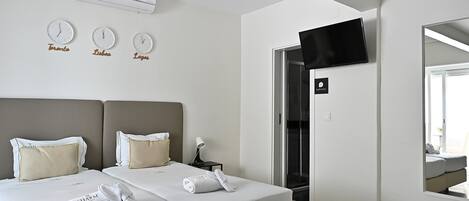 A hotel room with two beds, a TV, an air conditioning unit, and a bathroom sign.