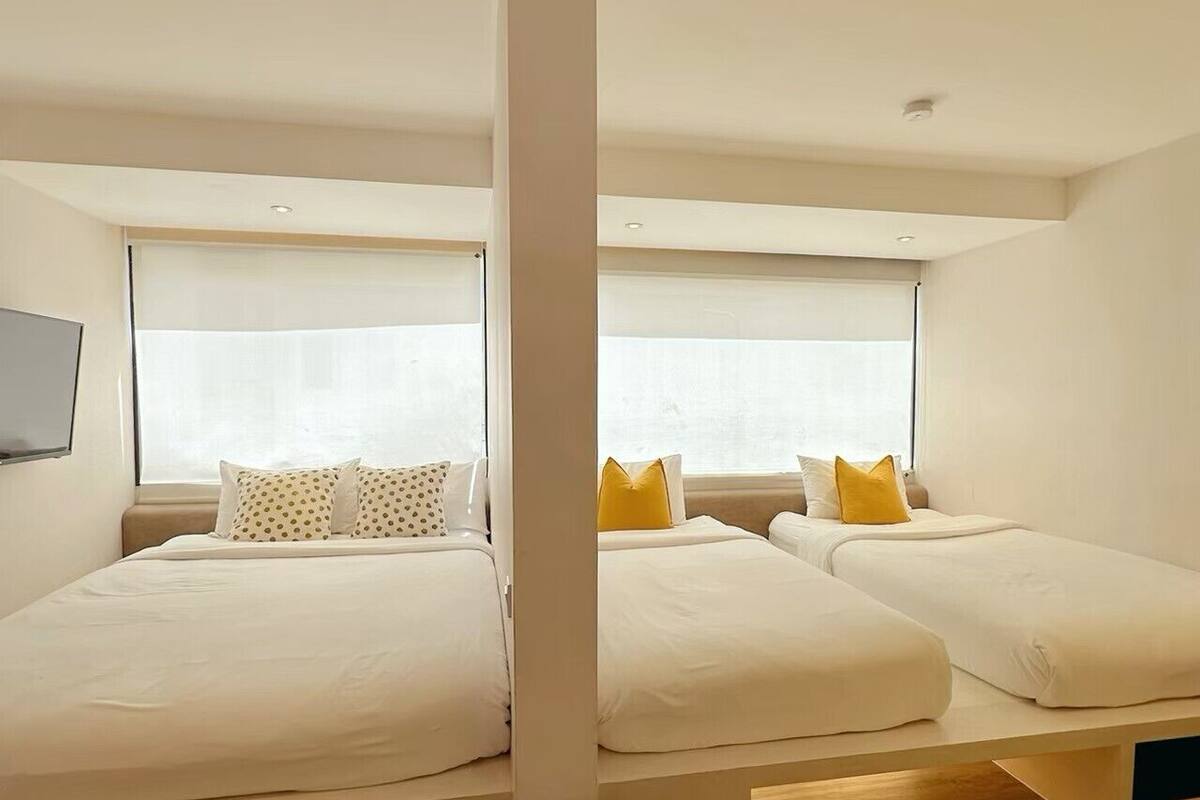 Een moderne slaapkamer met twee bedden, een houten vloer en een groot raam.