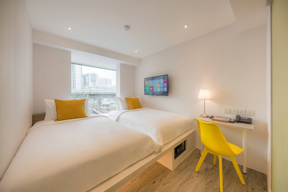 Hotelkamer met een bed, bureau, stoel, televisie en raam met uitzicht op de stad.