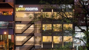Ein modernes Hotel mit der Aufschrift "yellow rooms", bestehend aus einem mehrstöckigen Gebäude mit Balkonen und einer Treppe.