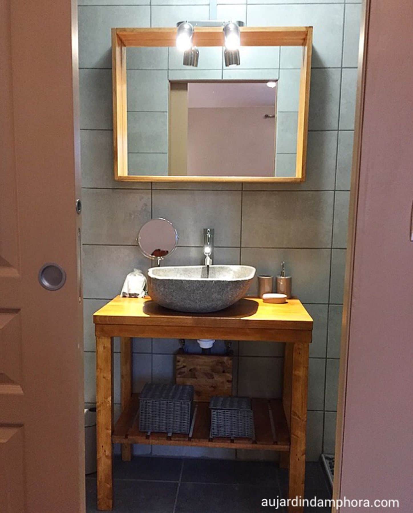 Et badeværelse med et trækommode, en sten vask, et spejl og en håndklædestang.
