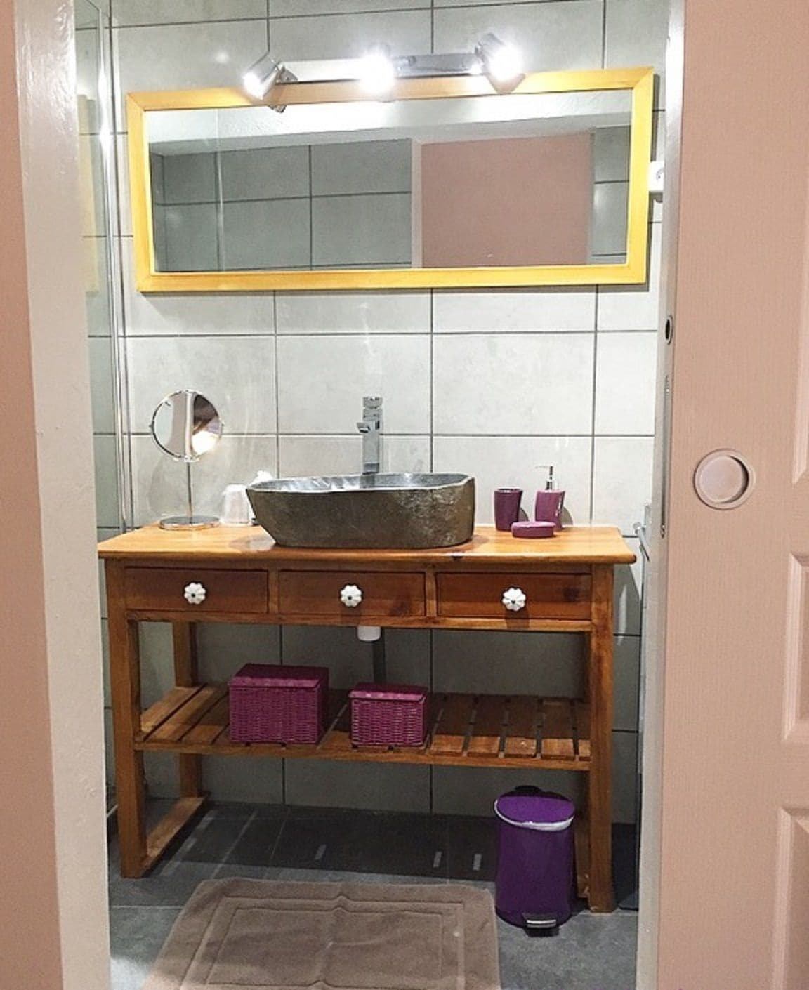 A bathroom with a wooden vanity, a large mirror, and a sink.