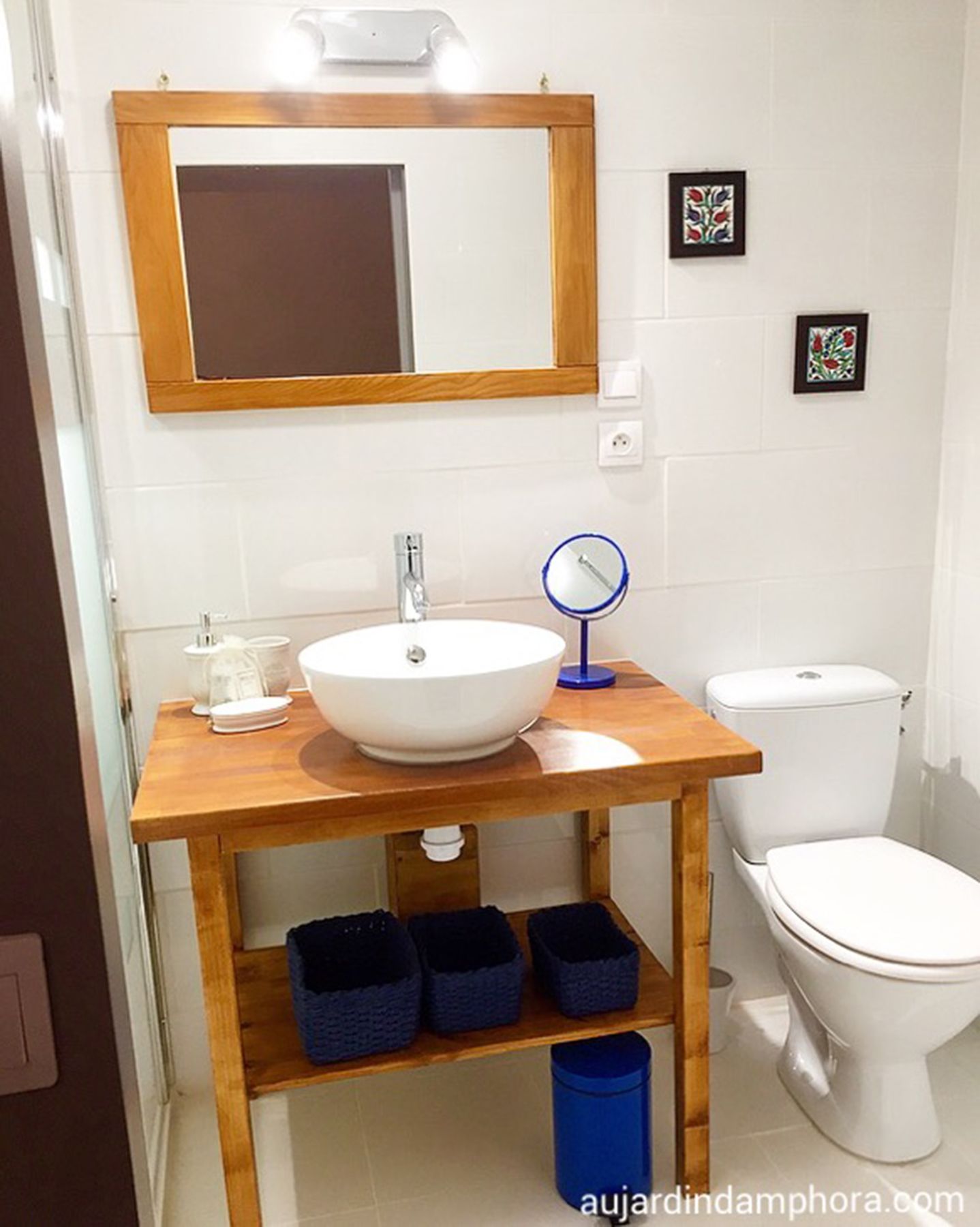 Une salle de bain avec un meuble-lavabo en bois, un lavabo blanc, un miroir et des toilettes.