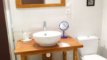 Une salle de bain avec un meuble-lavabo en bois, un lavabo blanc, un miroir et des toilettes.