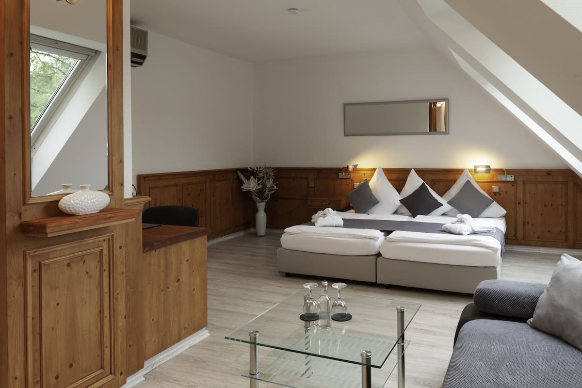 A modern room with a glass coffee table, a sofa, a bed with a headboard, a wooden reception desk, and a large window.