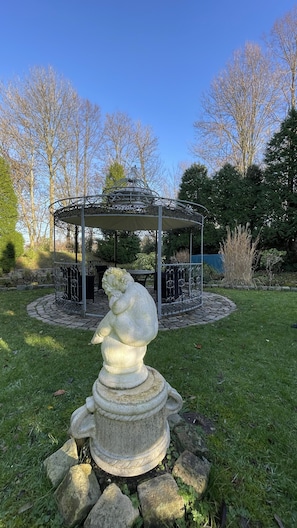 A gazebo with a stone sculpture in front. - Hotel Haus Gimken (Essen)