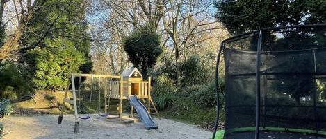 A playground with a slide, swings, and a trampoline.