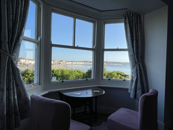 A corner room with a bay window overlooking a beach and cityscape. - The Lantana (Weymouth)