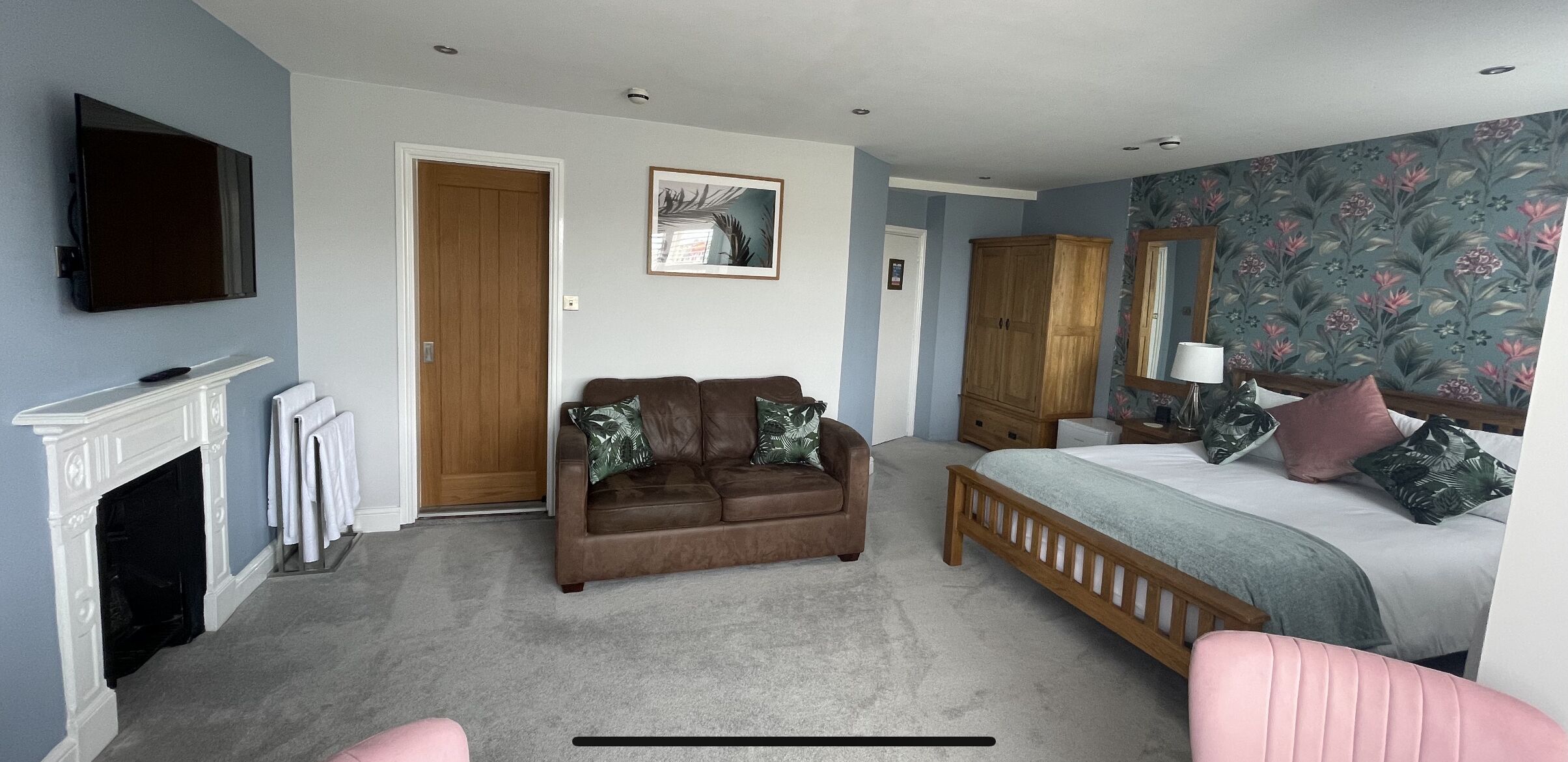 Une chambre avec une cheminée, un canapé, un lit, une armoire et un téléviseur.