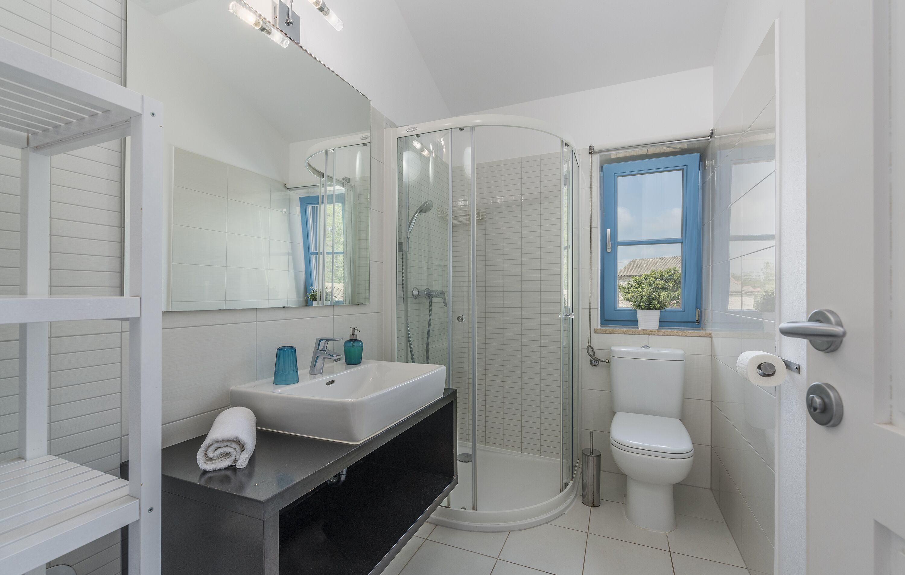 A modern bathroom with a glass-enclosed shower, a white sink, and a toilet.