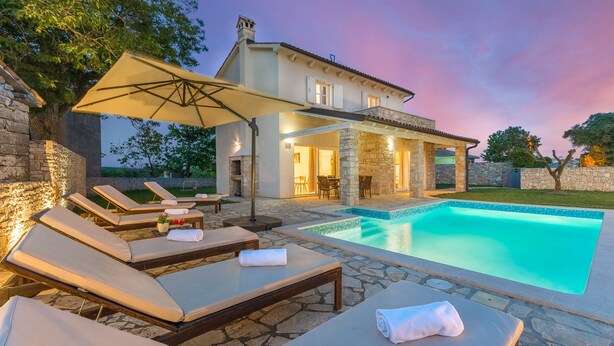 A poolside area with lounge chairs and a stone wall. - Villas Adagio (Barban)
