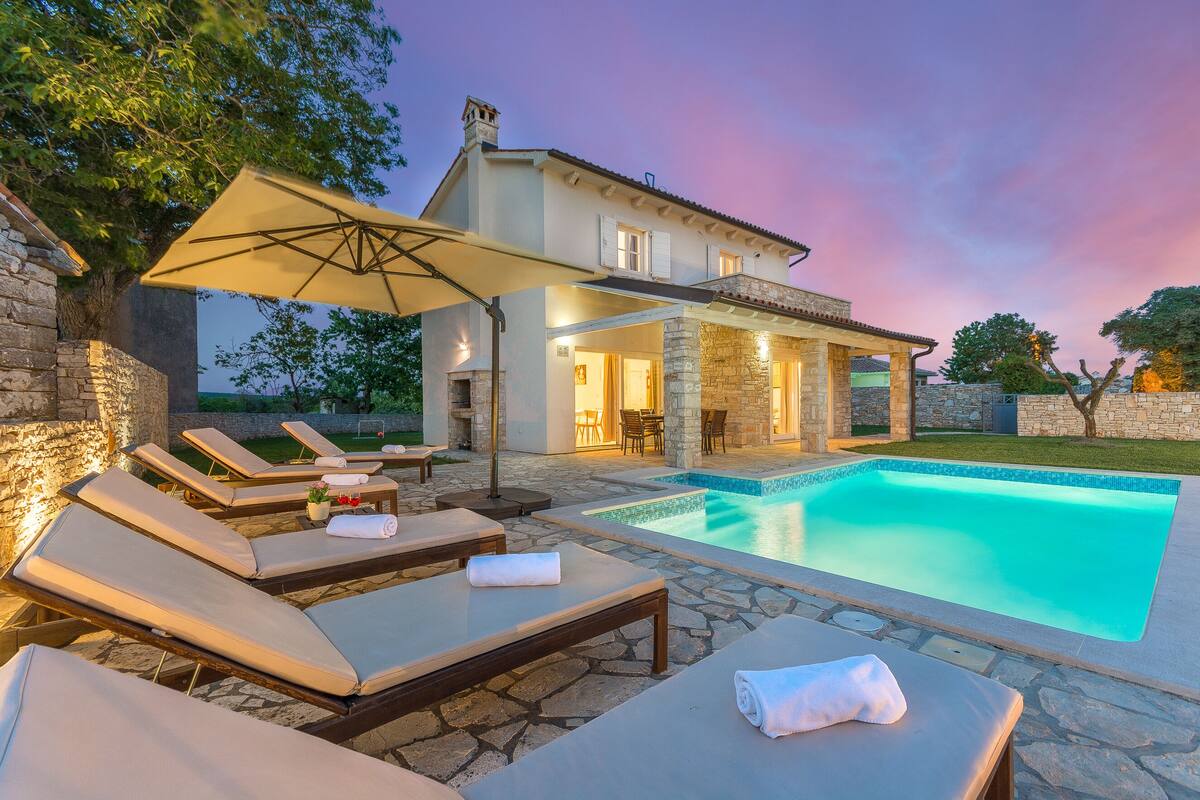 A poolside area with lounge chairs and a stone wall.