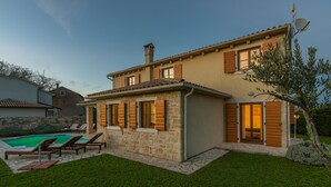 A two-story house with a stone facade, wooden shutters, and a swimming pool in the backyard. - Villas Adagio (Barban)