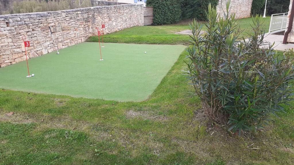 Un parcours de mini-golf comportant trois trous signalés par des drapeaux rouges.