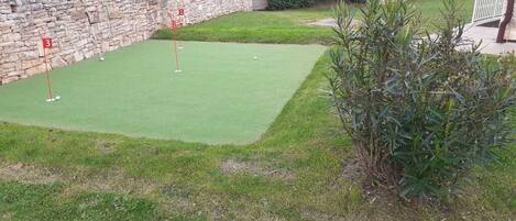 Un parcours de mini-golf comportant trois trous signalés par des drapeaux rouges.