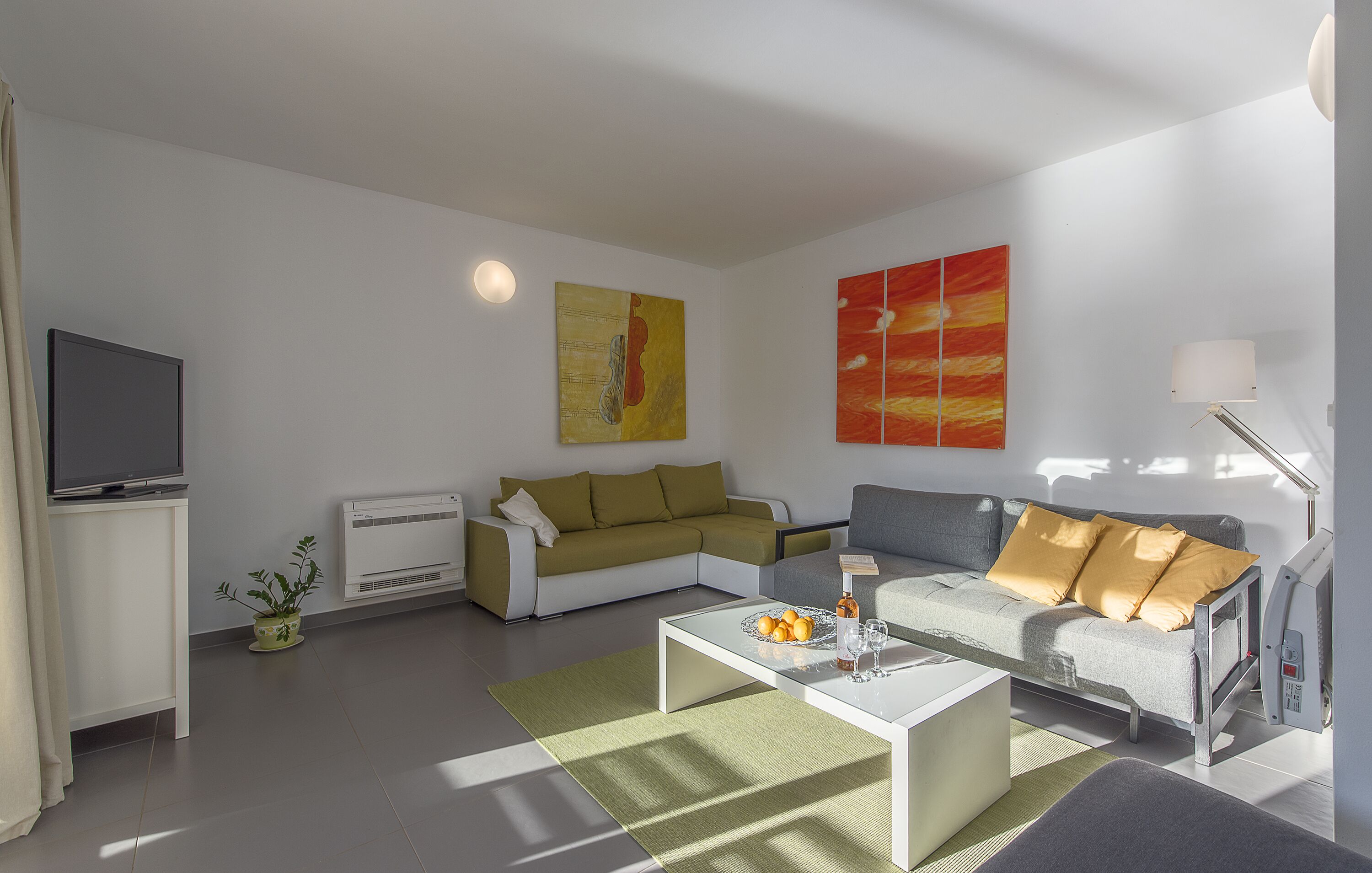 A modern living room with a sectional sofa, a flat-screen TV, and artwork on the walls.