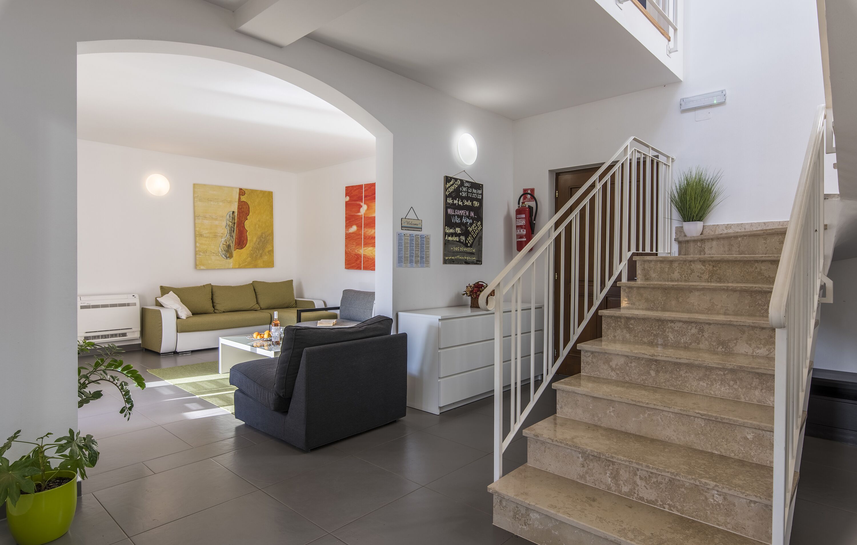 Una sala moderna con una escalera, un sofá, una mesa de centro y una zona de comedor.