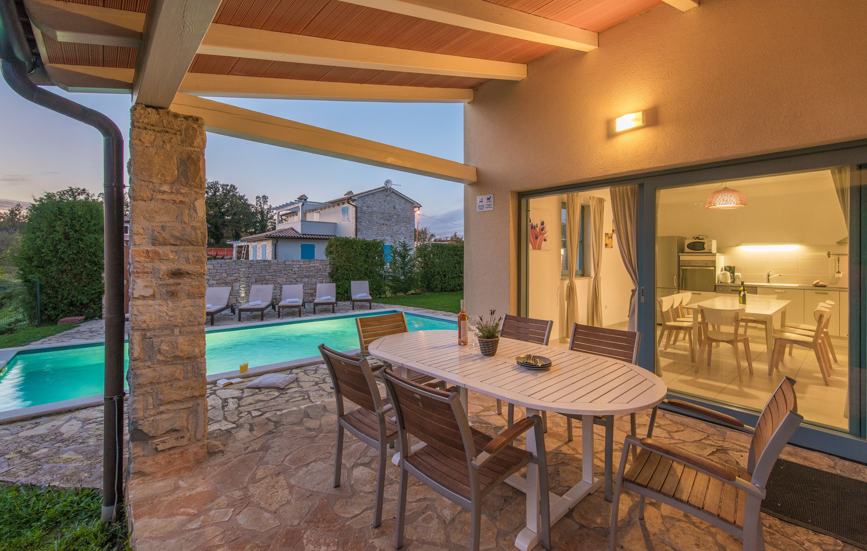 A patio with a pool, outdoor seating, and a view of the backyard.
