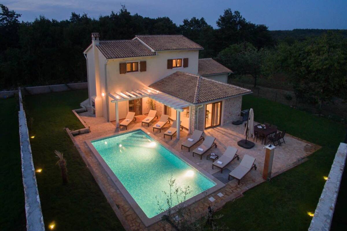 A two-story house with a swimming pool, outdoor seating, and a covered patio area.
