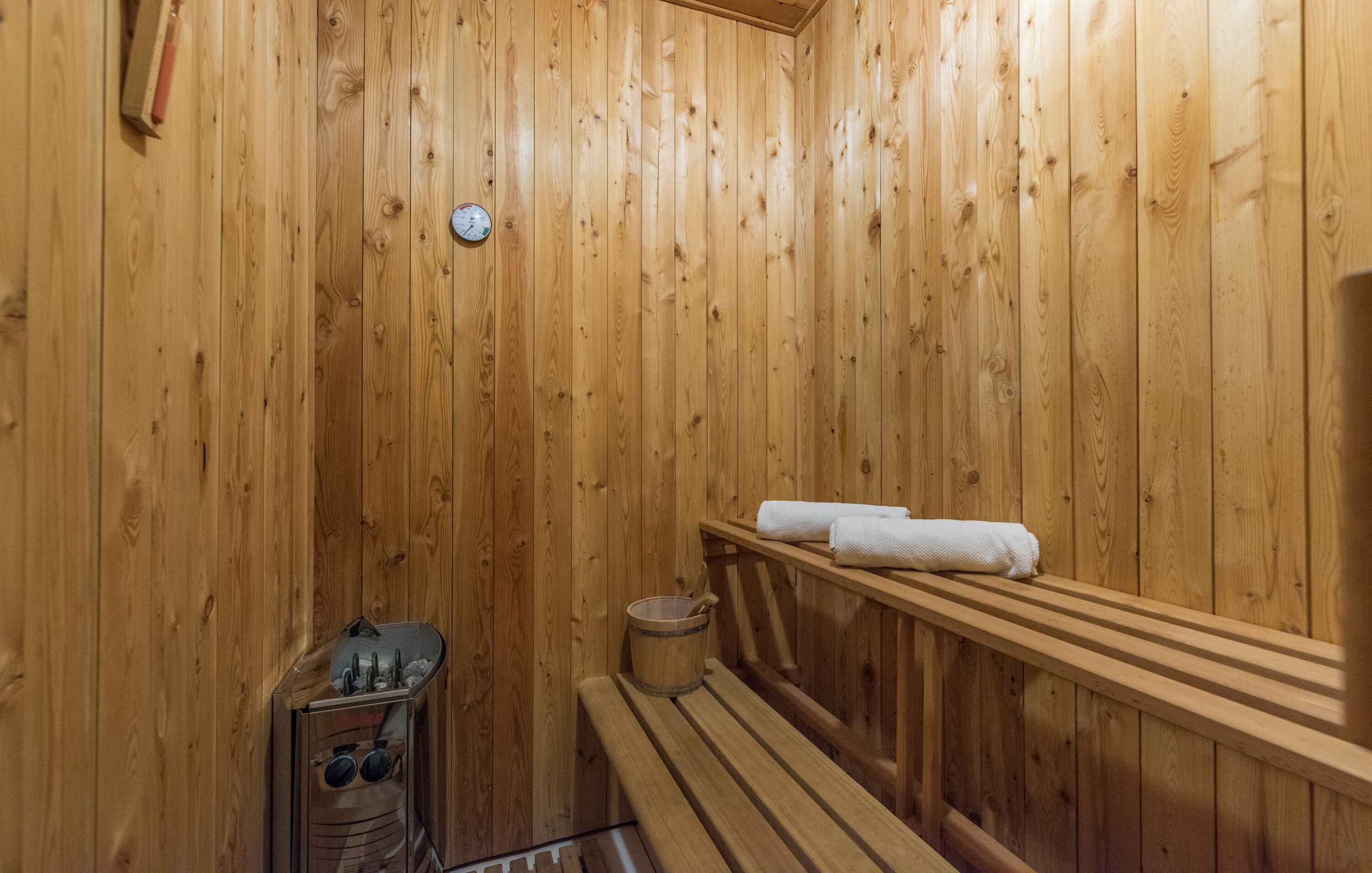Een houten sauna met banken en een houtkachel.