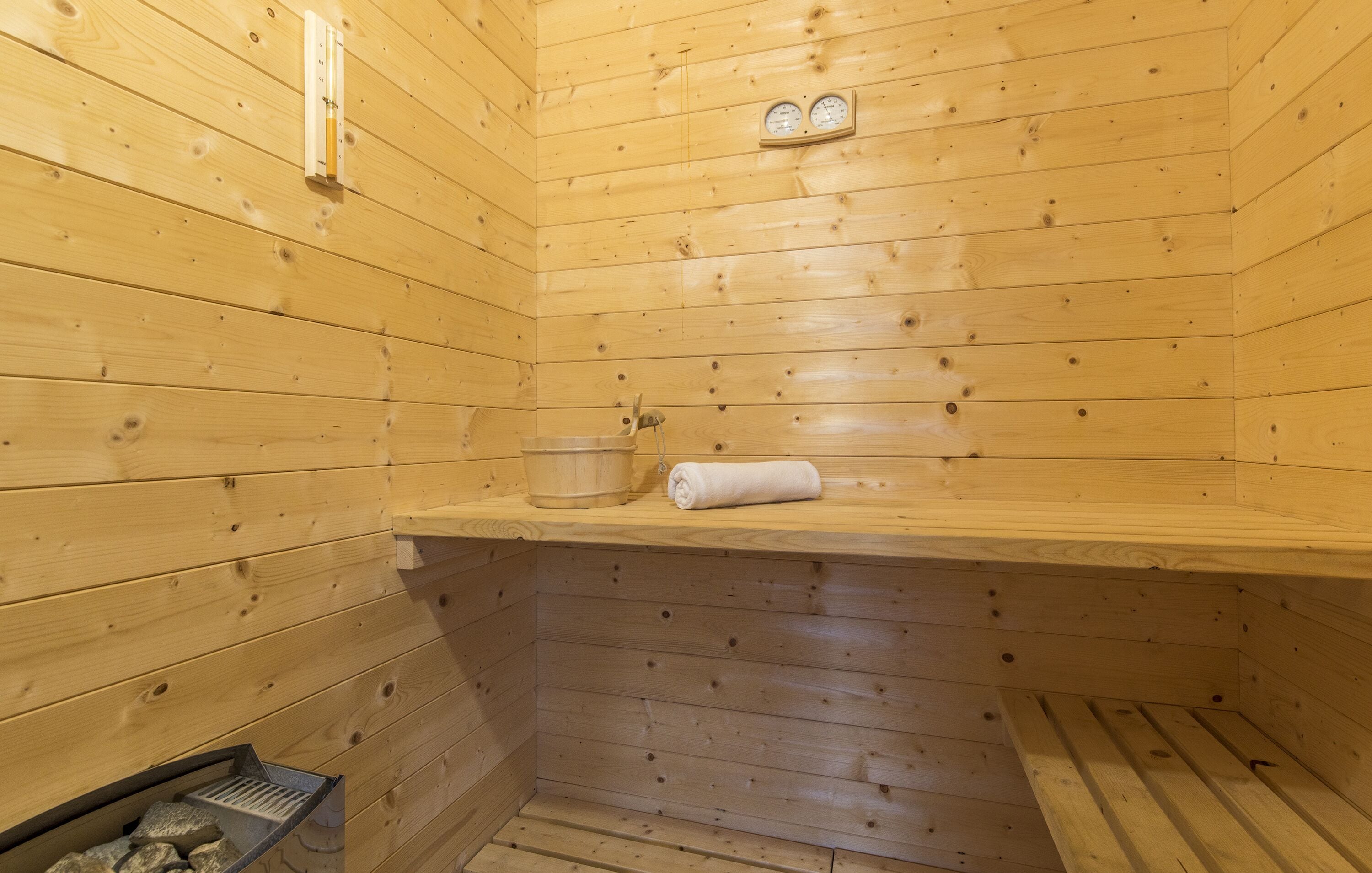 Un sauna en bois avec un banc, une serviette et un thermomètre accroché au mur.