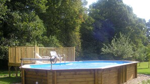 A rectangular above-ground pool with a wooden deck, a slide, and a couple of lounge chairs. - Les Sapins (Vitry-aux-Loges)