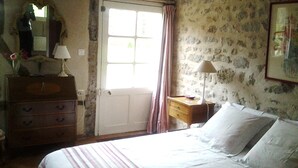 A bedroom with a bed, dresser, mirror, and a door leading outside. - Les Sapins (Vitry-aux-Loges)