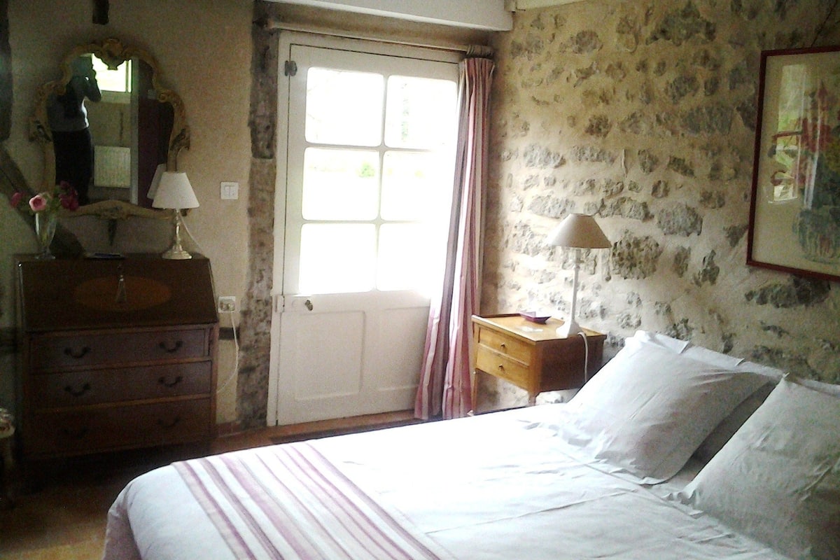 A bedroom with a bed, dresser, mirror, and a door leading outside.
